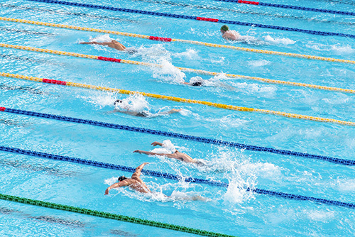 Swimmers competing in a pool with lanes